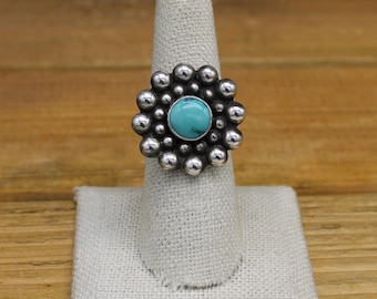 May include: A silver ring with a turquoise stone set in a cluster of silver beads.