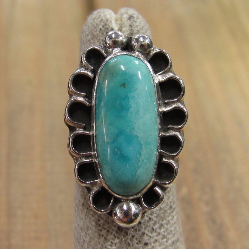 May include: A silver ring with a turquoise stone set in a scalloped design.