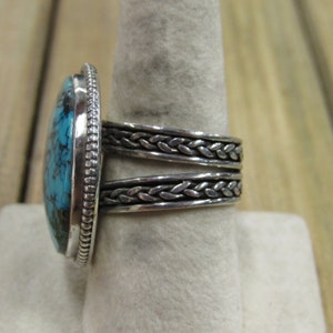 May include: A silver ring with a braided band and a large oval turquoise stone.