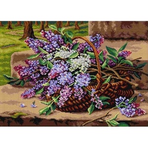 Op de afbeelding: Een rieten mand vol met paarse en witte lila bloemen. De mand staat op een stenen trede met een groene gras achtergrond.