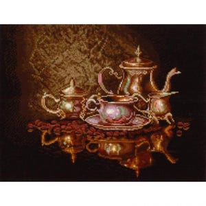 May include: A still life image of a coffee set, including a cup and saucer, sugar bowl, creamer, and a coffee pot. The set is a metallic gold colour, with a reflective surface. Coffee beans are scattered around the set.