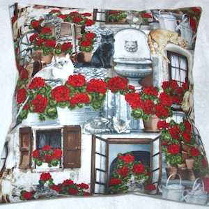Cats and bright red Geraniums on the patio cushion