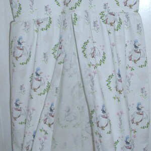 May include: A white diaper caddy with a hanging loop and a drawstring closure. The fabric features a repeating pattern of blue ducks and pink flowers on a white background.