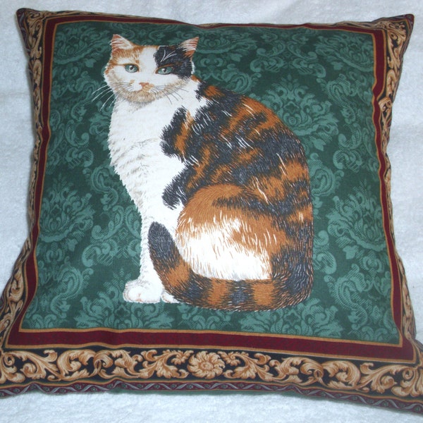 A very pretty marmalade and white cat on a green background cushion, pillow