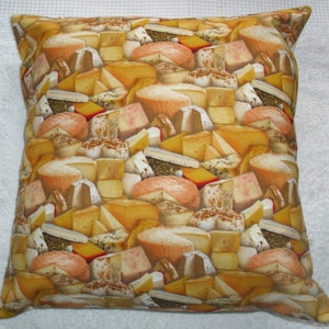 May include: Square pillow with a repeating pattern of various cheeses in shades of yellow, orange, and white. The pillow has a soft, textured appearance, suggesting a comfortable design for home decor.