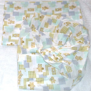 May include: White fitted sheet with a checkered pattern in shades of green, blue, and yellow. The sheet is decorated with a repeating pattern of small teddy bears.