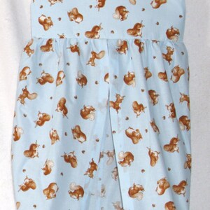 May include: A light blue diaper stacker with a squirrel print. The stacker has a white fabric panel at the bottom and a metal hanger at the top.