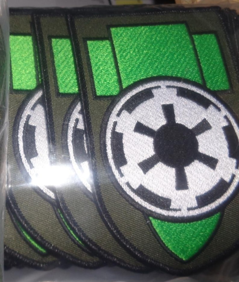 Puede incluir: Un conjunto de cinco parches bordados verdes y negros con el s&iacute;mbolo imperial de Star Wars. Los parches est&aacute;n sobre un fondo verde con un borde blanco.