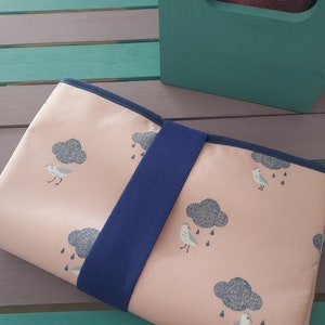 Può includere: Una borsa per il pranzo in tessuto rosa con un cinturino blu. La borsa ha un motivo di uccelli bianchi e nuvole grigie con gocce di pioggia.