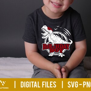 May include: A child wearing a dark grey t-shirt with a white dinosaur graphic and the text "Birthday Boy".
