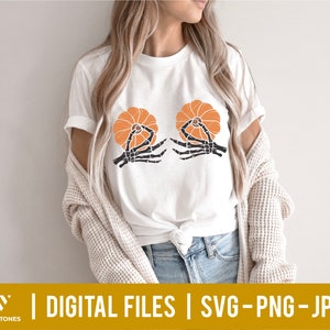 May include: A white t-shirt with a graphic of two skeleton hands holding orange pumpkins. The text "DIGITAL FILES | SVG - PNG - JPG" is at the bottom of the image.