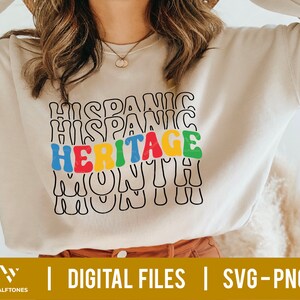 May include: A white sweatshirt with the text "HISPANIC HERITAGE MONTH" in colorful, wavy letters.