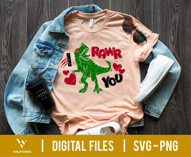May include: A light pink t-shirt with a green dinosaur graphic and the text "I Rawr You". The dinosaur is wearing a red headband and has hearts around it.
