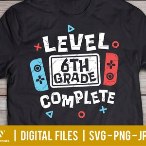 May include: Black t-shirt with a white graphic design that says "Level 6th Grade Complete" with a red and blue video game controller on either side of the text.