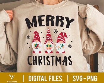 May include: A beige sweatshirt with the text "Merry Christmas" in black lettering. Three gnomes are depicted below the text, each wearing a red hat with white trim and holding a Christmas-themed item. The gnomes are standing on a white background.