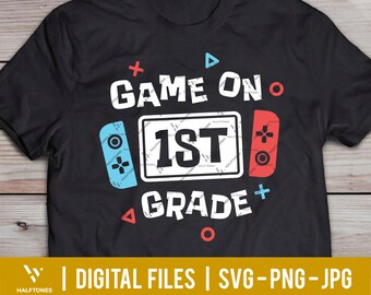 May include: Black t-shirt with a white graphic design that says "Game On 1st Grade" with a blue and red video game controller design on either side of the text.
