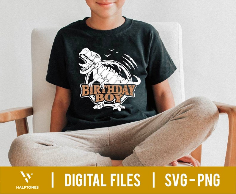 May include: A black t-shirt with a white dinosaur graphic and the text "Birthday Boy" in brown letters. The dinosaur is surrounded by a brown circle with a white outline.