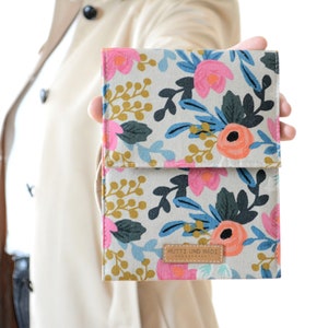 Può includere: Una pochette in tessuto con motivo floreale e un'etichetta in pelle marrone che dice "MUTTI UNO MADE".