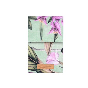 May include: A green fabric pouch with a floral print featuring pink flowers and green leaves. The pouch has a brown leather label with the text "MUTZ UND MADL" and "AUSTRIA" printed on it.