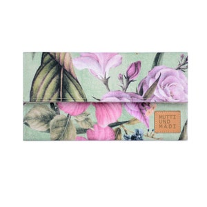 Puede incluir: Un embrague de tela con estampado floral verde con un parche de cuero marrón que dice "MUTTI UND MADI".