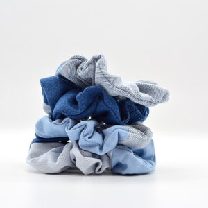Könnte beinhalten: Ein Stapel Jeans-Haargummis in verschiedenen Blau- und Grautönen. Die Haargummis sind aus weichem Stoff gefertigt und vor weißem Hintergrund übereinander gestapelt. Diese Haaraccessoires sind perfekt, um jedem Haarschnitt einen Hauch von Stil zu verleihen.