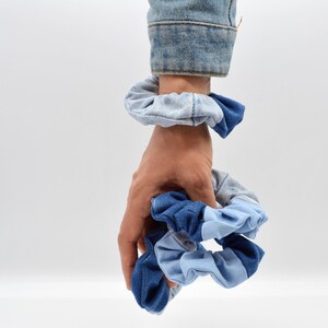 Könnte beinhalten: Ein Set mit drei blauen und hellblauen Haargummis aus Jeansstoff.