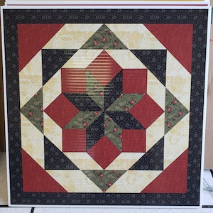 May include: A quilt block featuring a star design in black, red and green fabrics. The fabric has a floral pattern.