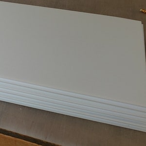 May include: A stack of white foam board sheets. The sheets are smooth and have a slightly textured surface.