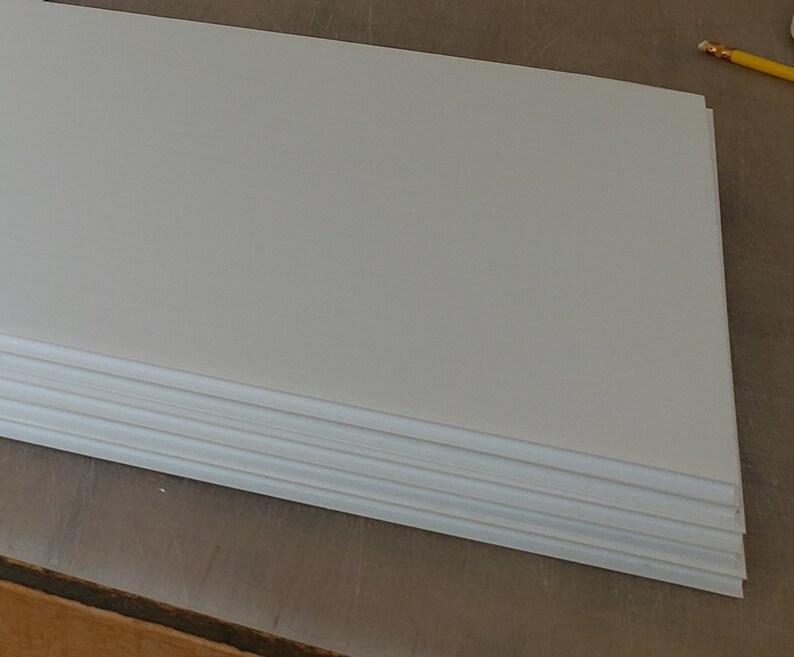 May include: A stack of white foam board sheets. The sheets are smooth and have a slightly textured surface.