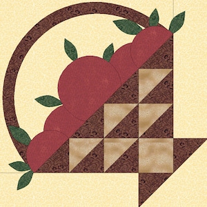 May include: A brown and beige patchwork quilt block with a circle design. The circle is filled with red circles and green leaves. The design resembles a basket of fruit.