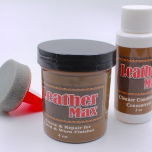 May include: A leather care kit featuring a brown jar with a black lid, a small bottle, and a sponge applicator. The jar and bottle are labeled "Leather Max" with text indicating they are for cleaning and conditioning leather. The jar contains 4 oz.