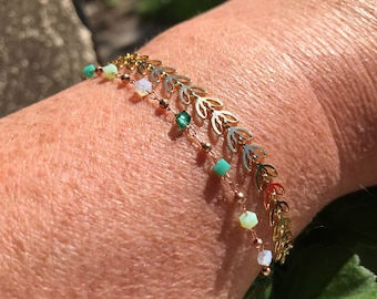 Puede incluir: Dos pulseras de hoja de oro con una cadena delicada y pequeñas cuentas verdes y blancas.