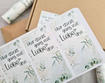 Puede incluir: Tres pegatinas rectangulares blancas con un diseño floral verde y dorado. El texto en las pegatinas dice "Hier steckt ganz viel Liebe drin".