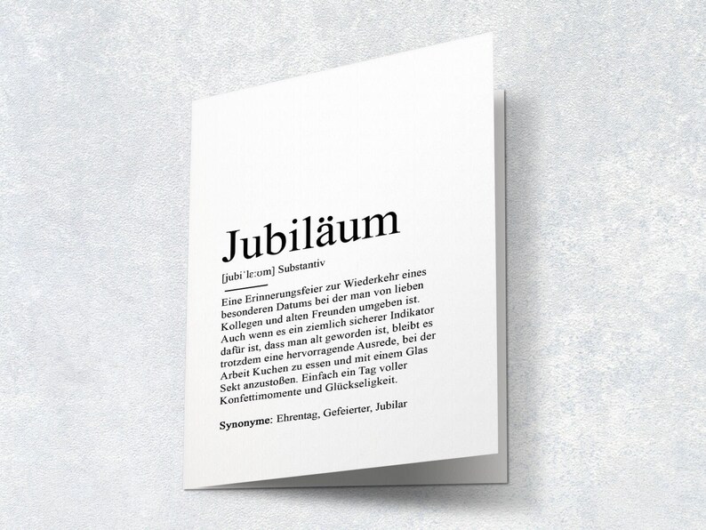 May include: A black and white printable definition card for the German word "Jubil&auml;um" which means "anniversary". The card defines the word as a celebration of a special date, often with colleagues and friends. It also mentions that it is a reminder of getting older, but a good excuse to have cake and champagne.