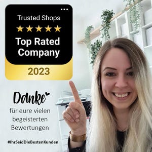 May include: A woman smiles and points at a black and gold Trusted Shops badge that reads "Top Rated Company 2023." The image also includes the German word "Danke" and text thanking customers. The background includes office equipment and greenery.