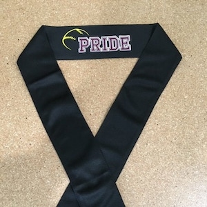 May include: Black neck gaiter with a yellow and black softball graphic and the word "PRIDE" in purple text.