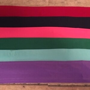 May include: Six fabric strips in different colors: red, black, pink, green, light blue, and purple. The strips are arranged in a stack, with the red strip on top and the purple strip on the bottom.