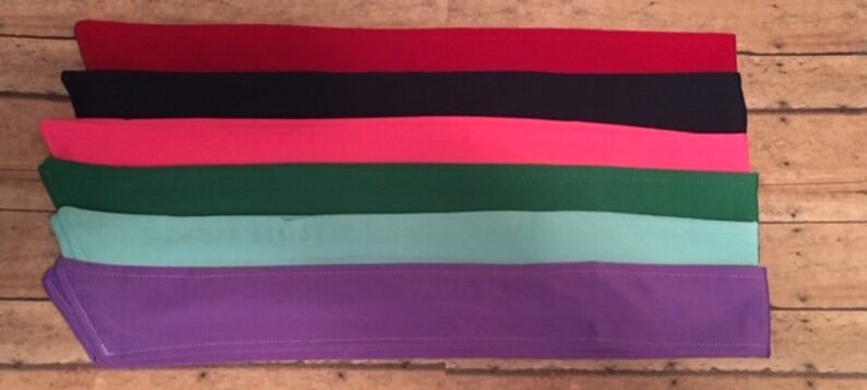 May include: Six fabric strips in different colors: red, black, pink, green, light blue, and purple. The strips are arranged in a stack, with the red strip on top and the purple strip on the bottom.