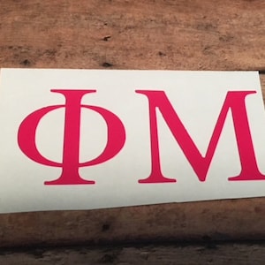 May include: A white sticker with the letters "ΦΜ" in bright pink.