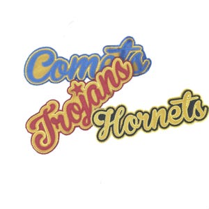 May include: Three embroidered patches with team names. The top patch reads "Comets" in blue and yellow. The middle patch says "Trojans" in red and gold. The bottom patch says "Hornets" in yellow and black.
