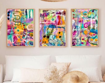 Puede incluir: Tres obras de arte abstractas enmarcadas con colores vibrantes. Cada obra presenta una mezcla de tonos rosa, amarillo, azul y verde, con pinceladas texturizadas y formas orgánicas. Los marcos son de color marrón claro y el arte se exhibe sobre un sofá blanco.