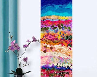 Op de afbeelding: Een kleurrijk abstract wandkunstwerk gemaakt met lagen vilt, stof en borduurwerk. Het stuk heeft een verscheidenheid aan kleuren, waaronder blauw, roze, geel en groen. Het stuk is ongeveer 30 cm breed en 60 cm hoog.