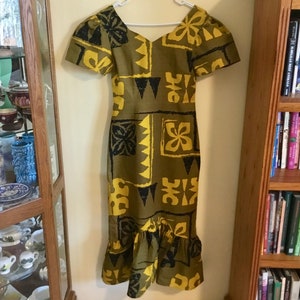 May include: A green and yellow dress with a geometric pattern. The dress has a ruffled hem and short sleeves.