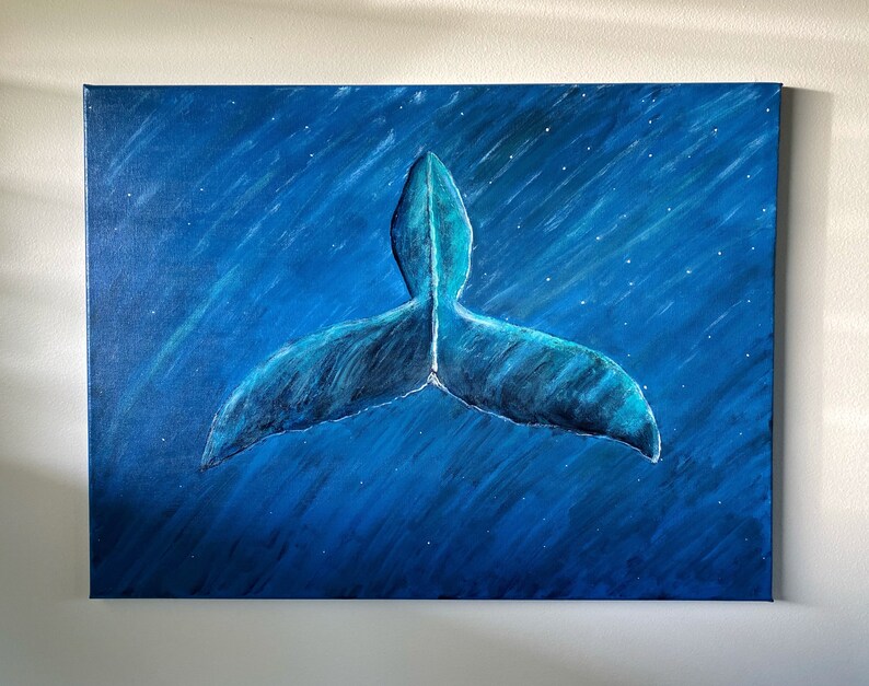 Puede incluir: Pintura en lienzo azul de la cola de una ballena, con tonos azules y blancos. La cola es el punto focal, sobre un fondo azul oscuro con motas blancas en forma de estrella, sugiriendo una escena submarina o nocturna.