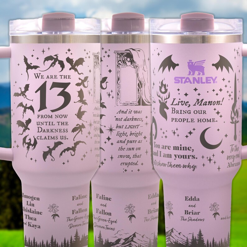 a set of three travel mugs sitting on top of a green field