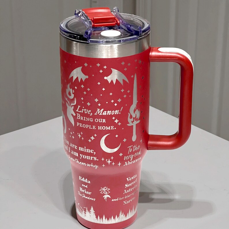 A red and silver insulated tumbler mug with a printed design and text on it, sitting on a white surface.