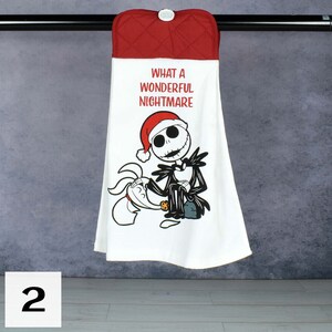 May include: White kitchen towel with a red quilted top and a button closure. The towel features a graphic of Jack Skellington in a Santa hat with the text "WHAT A WONDERFUL NIGHTMARE". A cartoon dog is also featured on the towel.