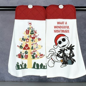 May include: Two white kitchen towels with red quilted tops, hanging from a metal bar. One towel features a Christmas tree design with Halloween-themed ornaments. The other towel has Jack Skellington and the text "WHAT A WONDERFUL NIGHTMARE."