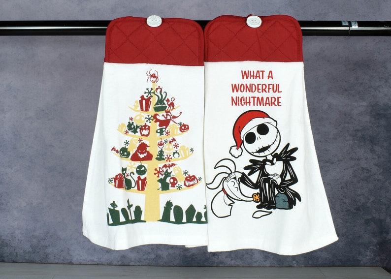 May include: Two white kitchen towels with red quilted tops, hanging from a metal bar. One towel features a Christmas tree design with Halloween-themed ornaments. The other towel has Jack Skellington and the text "WHAT A WONDERFUL NIGHTMARE."