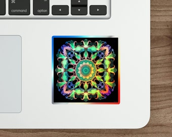 May include: A square sticker with a vibrant, colorful mandala design. The mandala features a symmetrical pattern with shades of green, blue, yellow, and red, set against a black background. The sticker has a thin, colorful border.